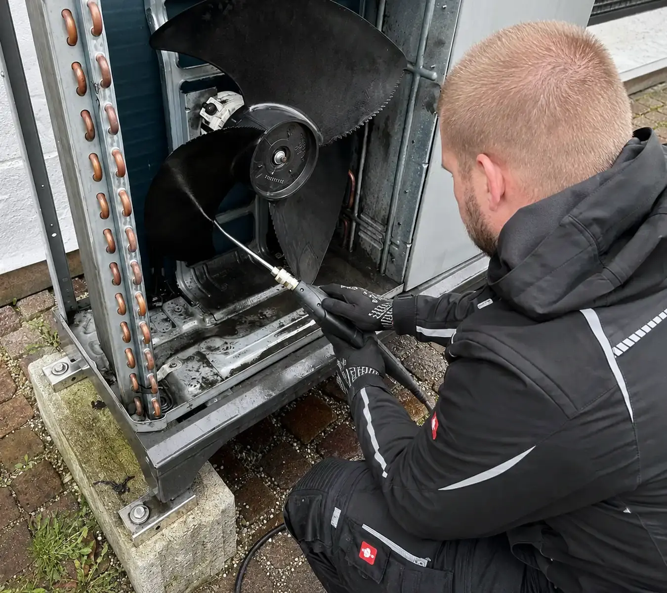 Wolfgang Schibath arbeitet am geöffneten Außengerät einer Wärmepumpe.